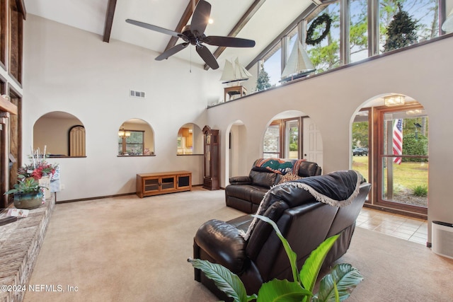 carpeted living room with a high ceiling, ceiling fan, and beamed ceiling