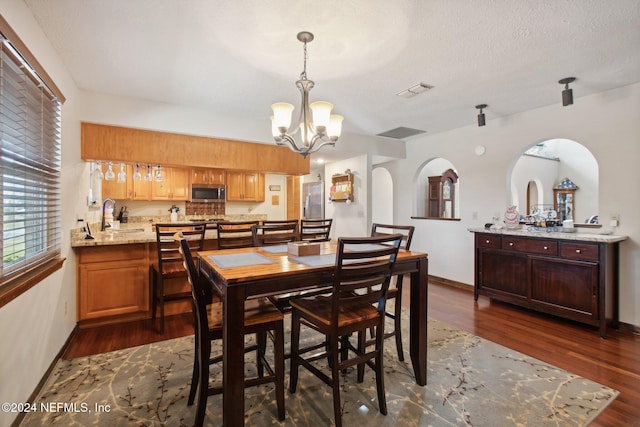 dining area with sink, a textured ceiling, a chandelier, and dark hardwood / wood-style floors