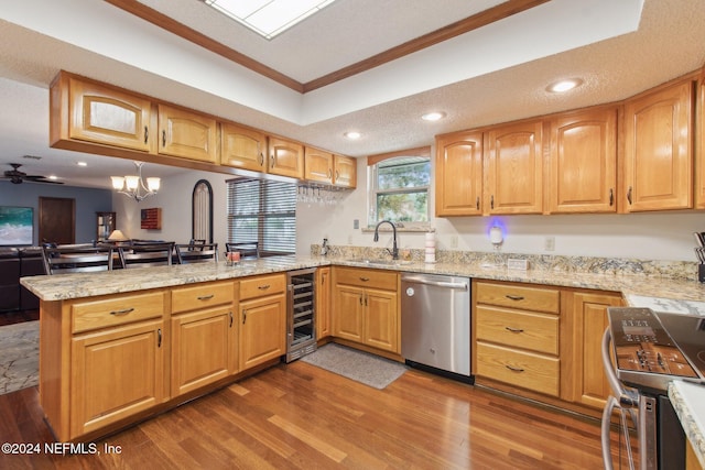 kitchen with beverage cooler, stainless steel appliances, kitchen peninsula, ornamental molding, and sink