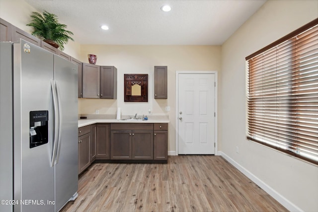 kitchen with light wood-type flooring, stainless steel fridge with ice dispenser, and sink