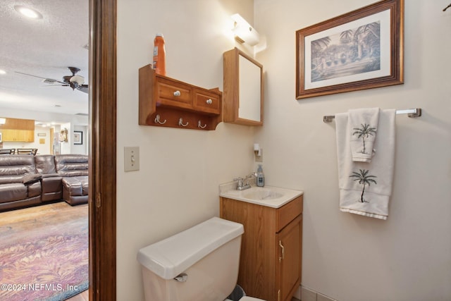 bathroom featuring toilet, vanity, a textured ceiling, and ceiling fan