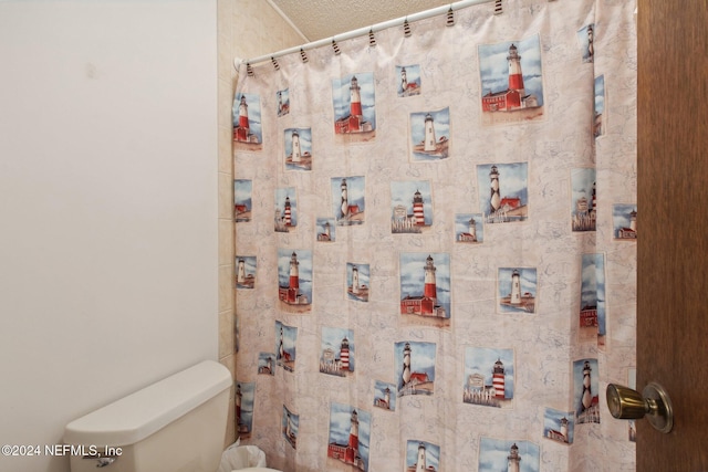 bathroom with a textured ceiling, a shower with shower curtain, and toilet