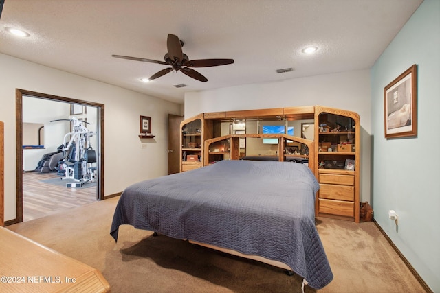 bedroom featuring a textured ceiling, ceiling fan, and light carpet