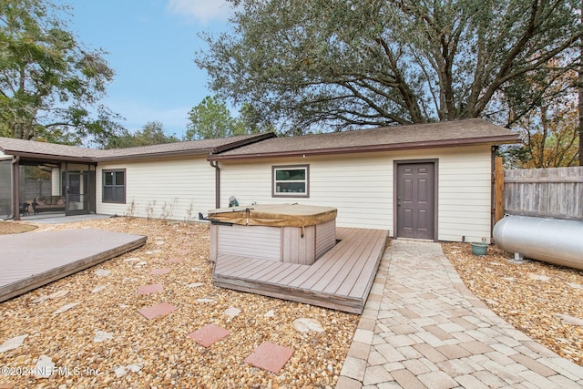 rear view of house with a deck, a hot tub, and a sunroom