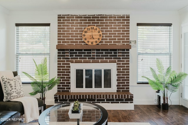 living room featuring a brick fireplace, dark wood-type flooring, and crown molding