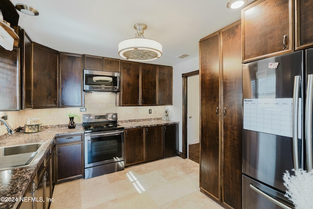 kitchen featuring light stone countertops, sink, stainless steel appliances, decorative light fixtures, and decorative backsplash