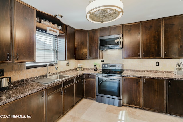 kitchen featuring dark stone countertops, dark brown cabinetry, sink, and appliances with stainless steel finishes