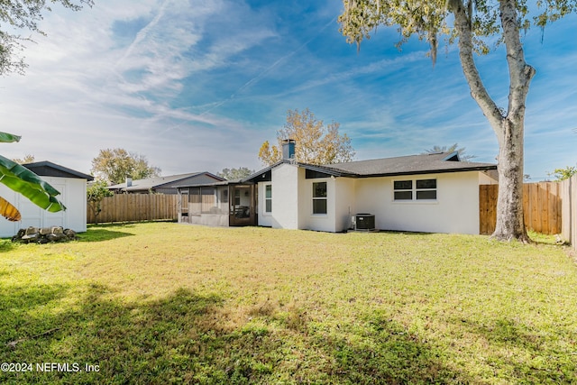 rear view of property featuring a yard, central air condition unit, and a sunroom