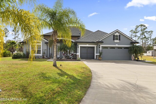 5321 Muskogean St, Saint Augustine, FL 32092 - view of front of property featuring stucco siding, a garage, concrete driveway, a front lawn, and roof with shingles
