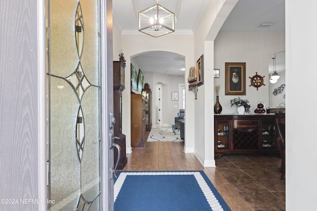 foyer with a notable chandelier, dark hardwood / wood-style flooring, and crown molding