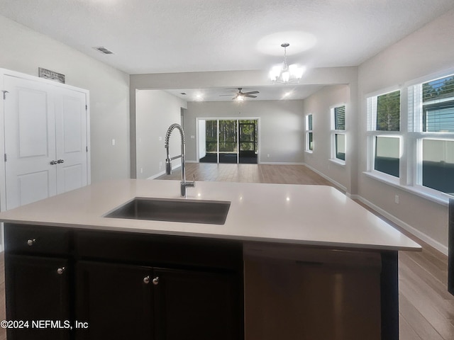 kitchen featuring a kitchen island with sink, ceiling fan with notable chandelier, sink, light hardwood / wood-style flooring, and a textured ceiling