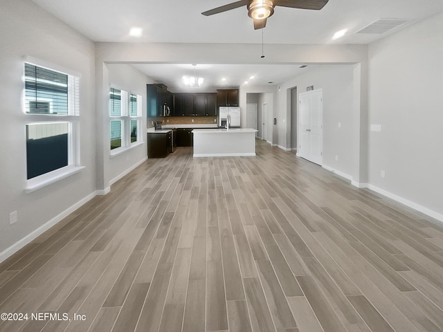 unfurnished living room featuring ceiling fan with notable chandelier and wood-type flooring