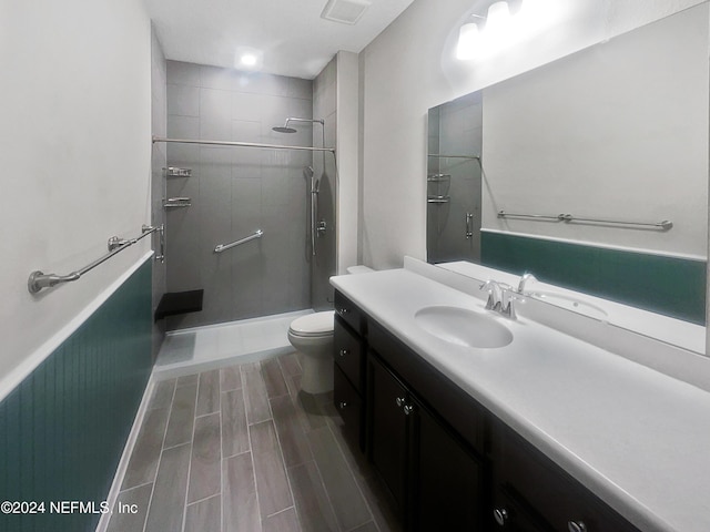 bathroom with tiled shower, vanity, and toilet