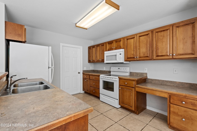 kitchen featuring light tile patterned flooring, white appliances, and sink