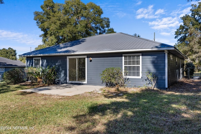 back of property with a lawn and a patio