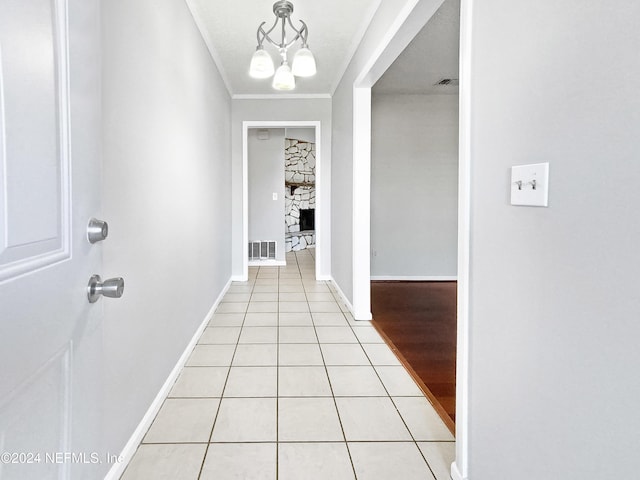 hall featuring light tile patterned floors, ornamental molding, and an inviting chandelier