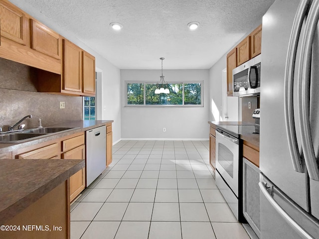 kitchen with sink, light tile patterned flooring, pendant lighting, and appliances with stainless steel finishes