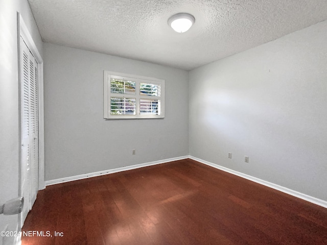 unfurnished bedroom featuring hardwood / wood-style flooring, a textured ceiling, and a closet