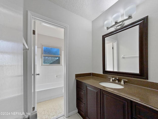 bathroom with tile patterned flooring, vanity, a textured ceiling, and tiled shower / bath