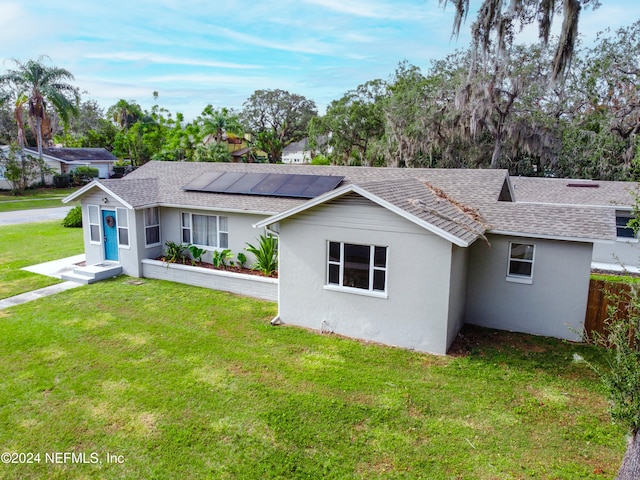 ranch-style house featuring solar panels and a front lawn