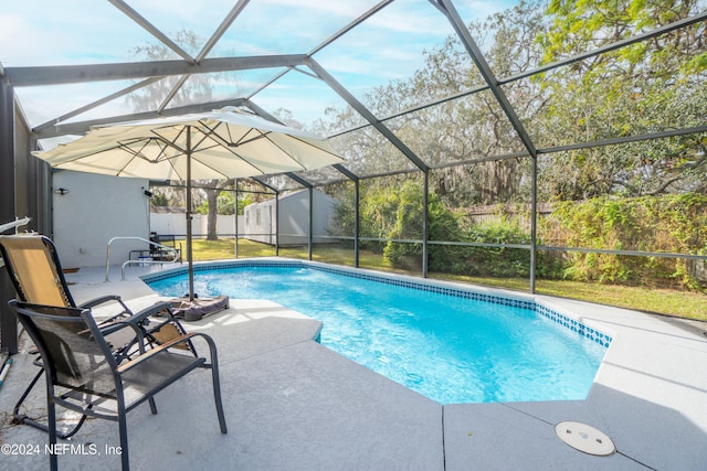 view of pool with a patio, glass enclosure, a shed, and a lawn