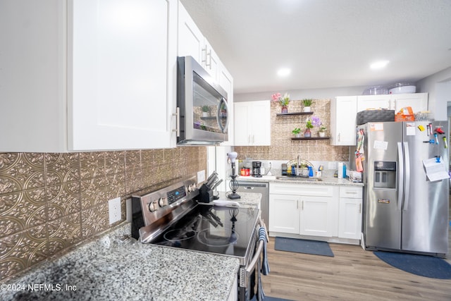 kitchen featuring tasteful backsplash, stainless steel appliances, sink, light hardwood / wood-style flooring, and white cabinetry