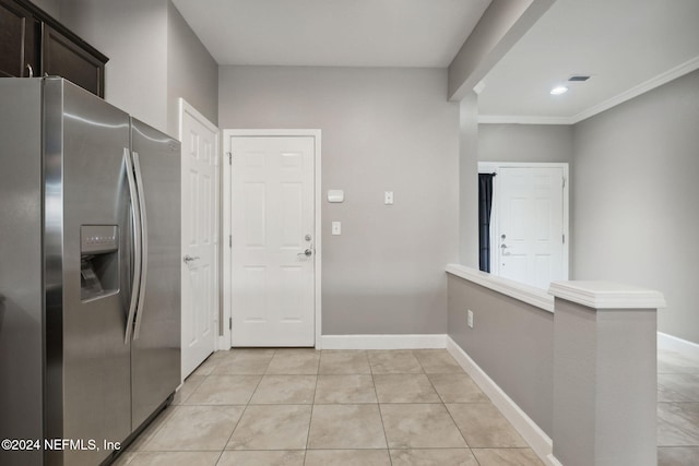 kitchen with stainless steel fridge, light tile patterned flooring, dark brown cabinetry, and ornamental molding