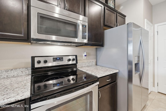 kitchen with light stone countertops, light tile patterned floors, dark brown cabinetry, and appliances with stainless steel finishes