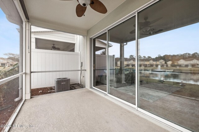 unfurnished sunroom with ceiling fan and a water view