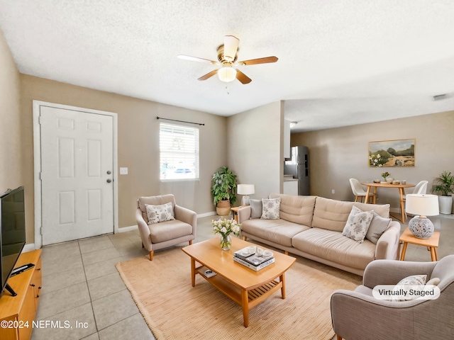 living room featuring ceiling fan, light tile patterned floors, and a textured ceiling