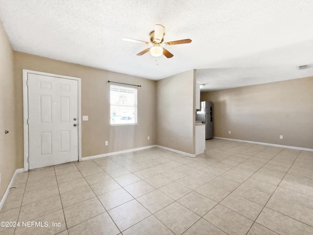 tiled spare room featuring a textured ceiling and ceiling fan