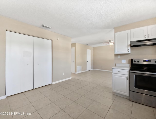 kitchen with stainless steel range with electric stovetop, a textured ceiling, ceiling fan, light tile patterned floors, and white cabinets