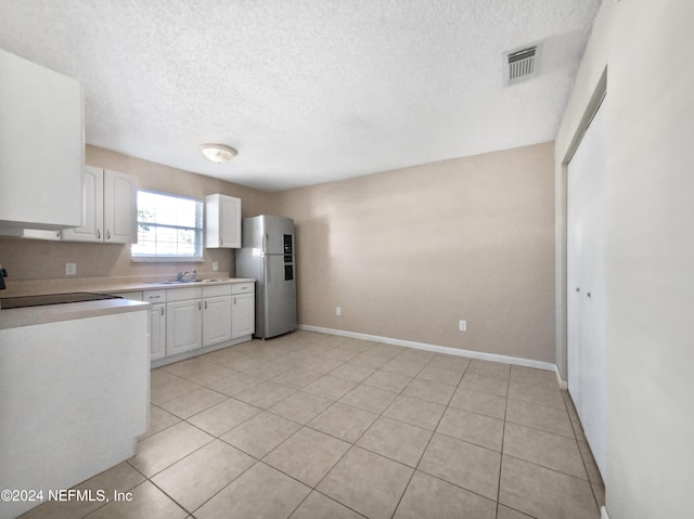 kitchen featuring stainless steel refrigerator, light tile patterned floors, white cabinets, and white stove