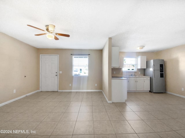 kitchen with stainless steel refrigerator, plenty of natural light, white cabinets, and sink