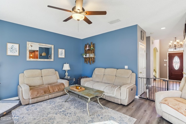 living room featuring hardwood / wood-style floors and ceiling fan with notable chandelier