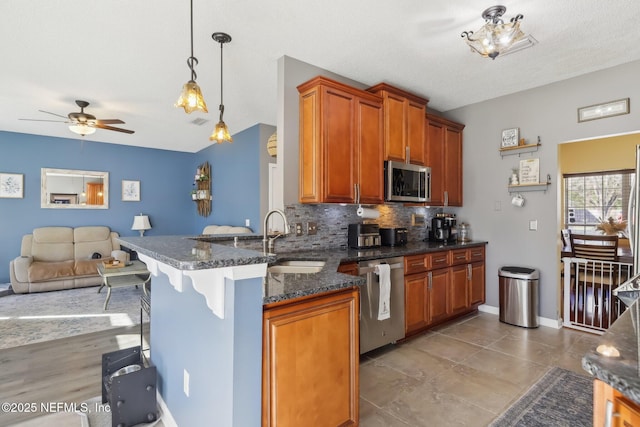 kitchen featuring kitchen peninsula, appliances with stainless steel finishes, hanging light fixtures, and sink