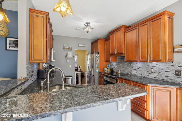 kitchen featuring kitchen peninsula, sink, dark stone counters, and appliances with stainless steel finishes