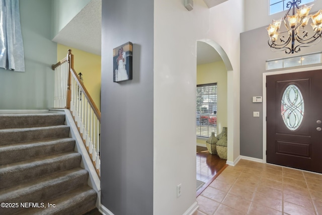 tiled foyer entrance featuring a notable chandelier, a towering ceiling, and a wealth of natural light