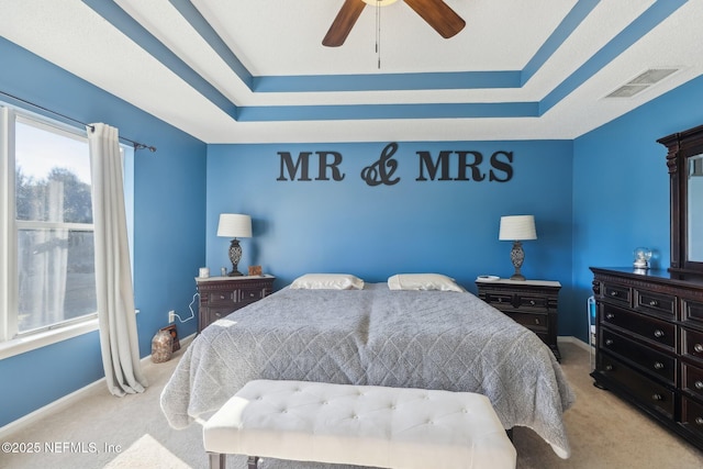 bedroom featuring ceiling fan, a raised ceiling, and light carpet