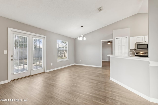 interior space with a notable chandelier, light hardwood / wood-style floors, lofted ceiling, and a textured ceiling