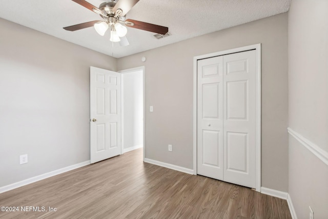 unfurnished bedroom with ceiling fan, a closet, a textured ceiling, and light wood-type flooring