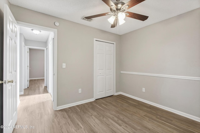 unfurnished bedroom with wood-type flooring, a closet, and ceiling fan