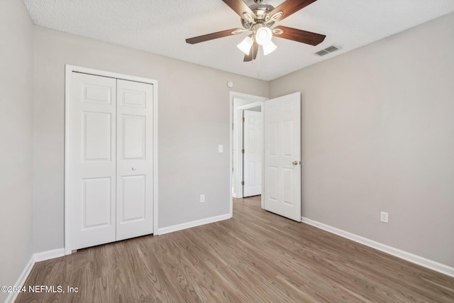 unfurnished bedroom featuring ceiling fan, light hardwood / wood-style floors, a textured ceiling, and a closet