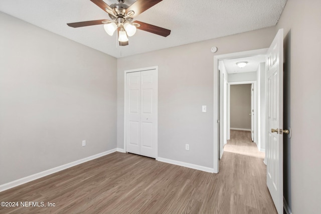 unfurnished bedroom with a textured ceiling, light wood-type flooring, a closet, and ceiling fan