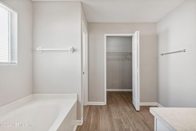 bathroom featuring a textured ceiling, vanity, hardwood / wood-style flooring, and a tub