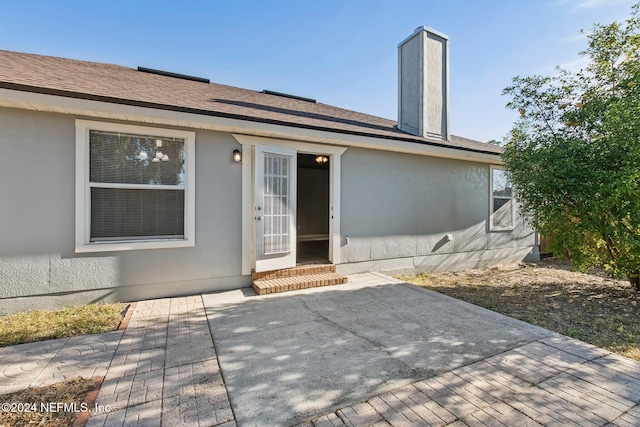 view of exterior entry with a patio