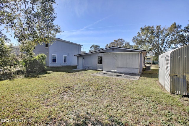 rear view of property with a storage shed and a lawn