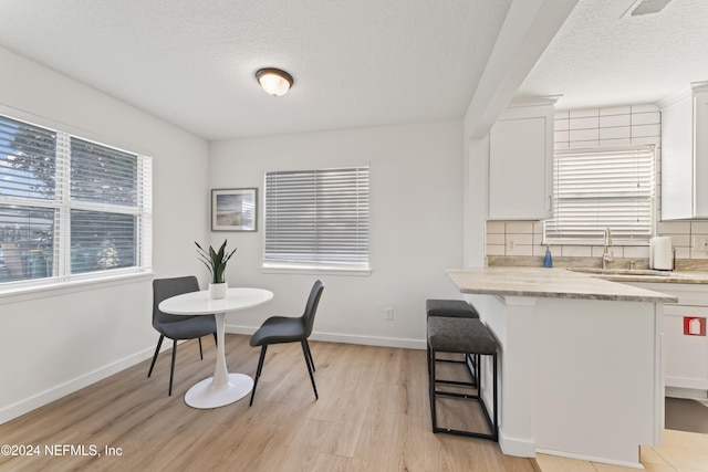 dining space with sink, a textured ceiling, and light wood-type flooring