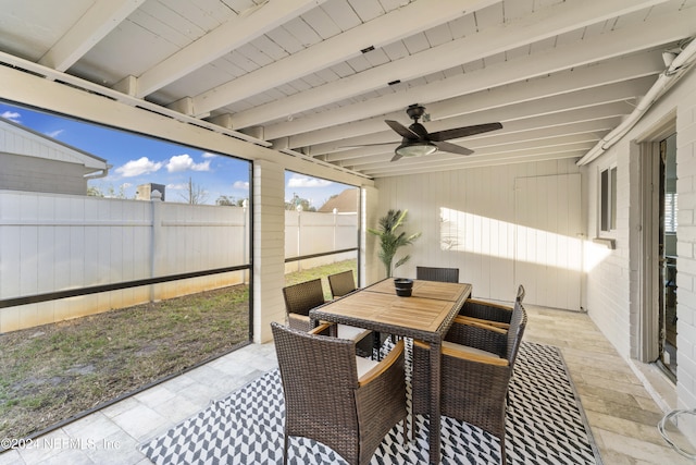 sunroom / solarium featuring ceiling fan and beam ceiling