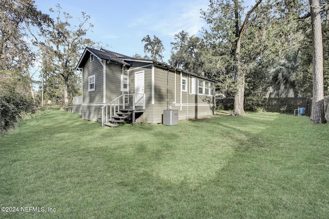 view of side of property featuring central AC and a yard